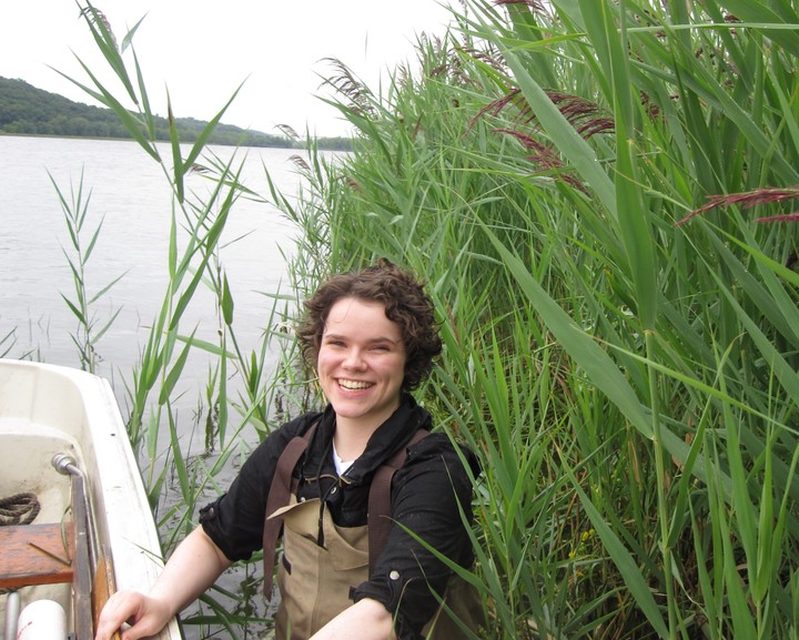 Photo of Dr. Alldred next to a boat with Phragmites in the background